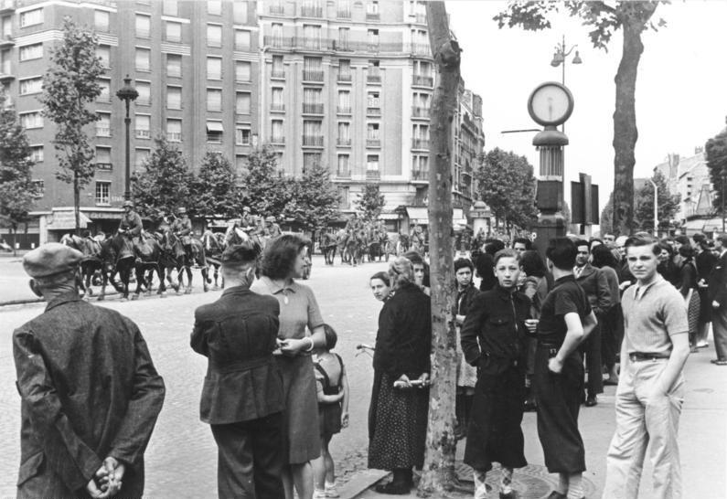 Historic photo shows a street in Paris lined with citizens watching Germans march into their city, photo title: Western Campaign, France, Paris – Entry of German troops; PK 698