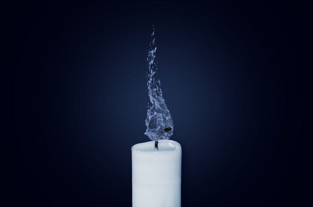 Photo of a white candlestick recently snuffed out with gray smoke rising from it 